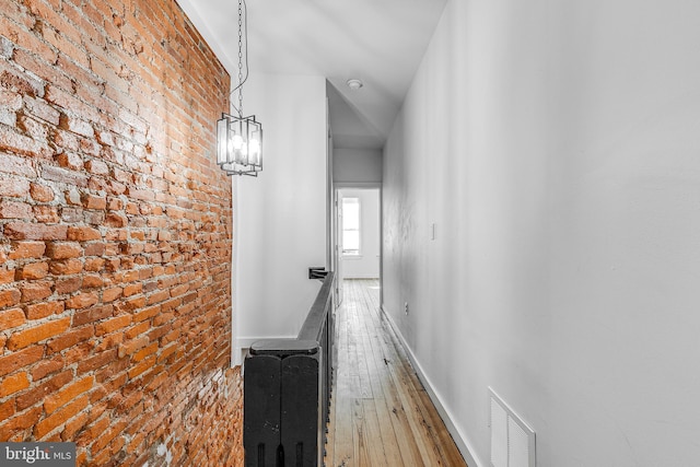 corridor featuring hardwood / wood-style flooring and brick wall