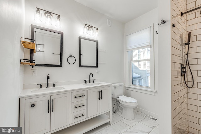 bathroom featuring vanity, tiled shower, and toilet