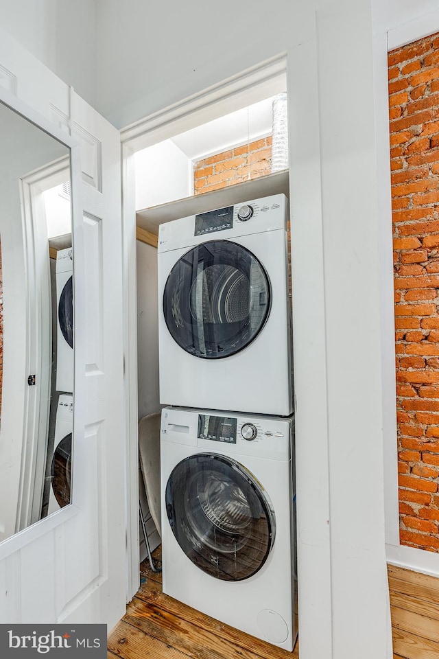 washroom with hardwood / wood-style floors and stacked washer and clothes dryer