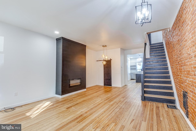 foyer entrance with brick wall, a fireplace, and light wood-type flooring