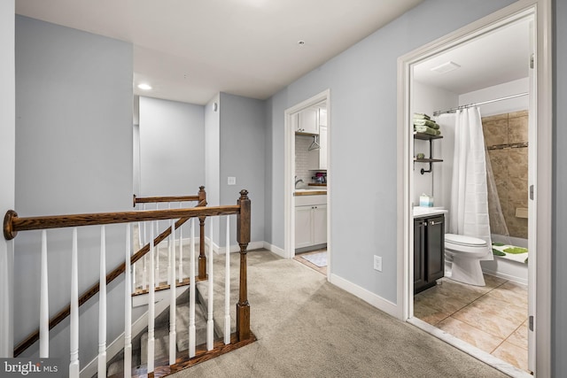 hall with sink and light carpet