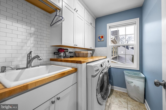 washroom featuring cabinets, light tile patterned flooring, sink, and washing machine and clothes dryer