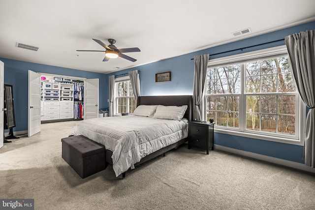 carpeted bedroom featuring ceiling fan, a spacious closet, and a closet