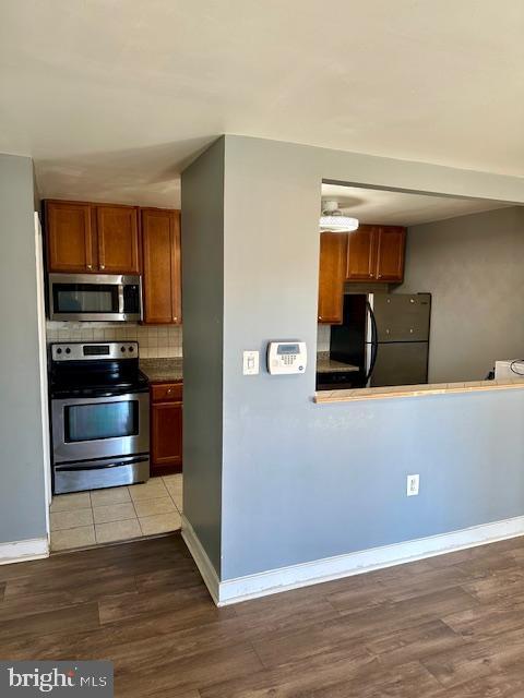 kitchen featuring hardwood / wood-style flooring, appliances with stainless steel finishes, and decorative backsplash