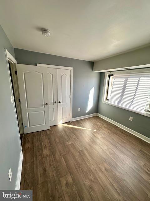 unfurnished bedroom featuring dark hardwood / wood-style flooring and a closet