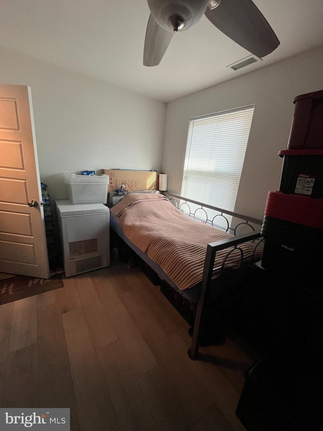 bedroom with a ceiling fan, visible vents, and wood finished floors