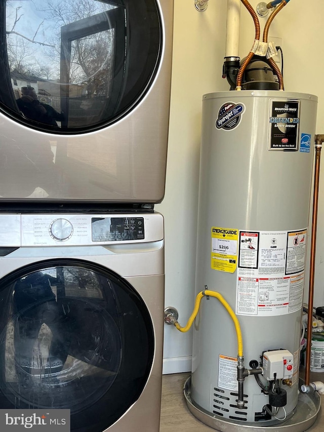 laundry area featuring light wood finished floors, laundry area, gas water heater, and stacked washer / dryer