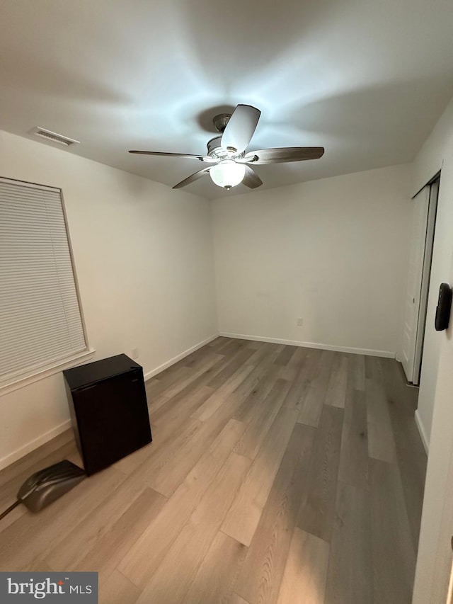 unfurnished bedroom featuring baseboards, visible vents, ceiling fan, and wood finished floors