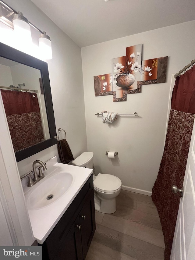 full bathroom featuring toilet, baseboards, and vanity