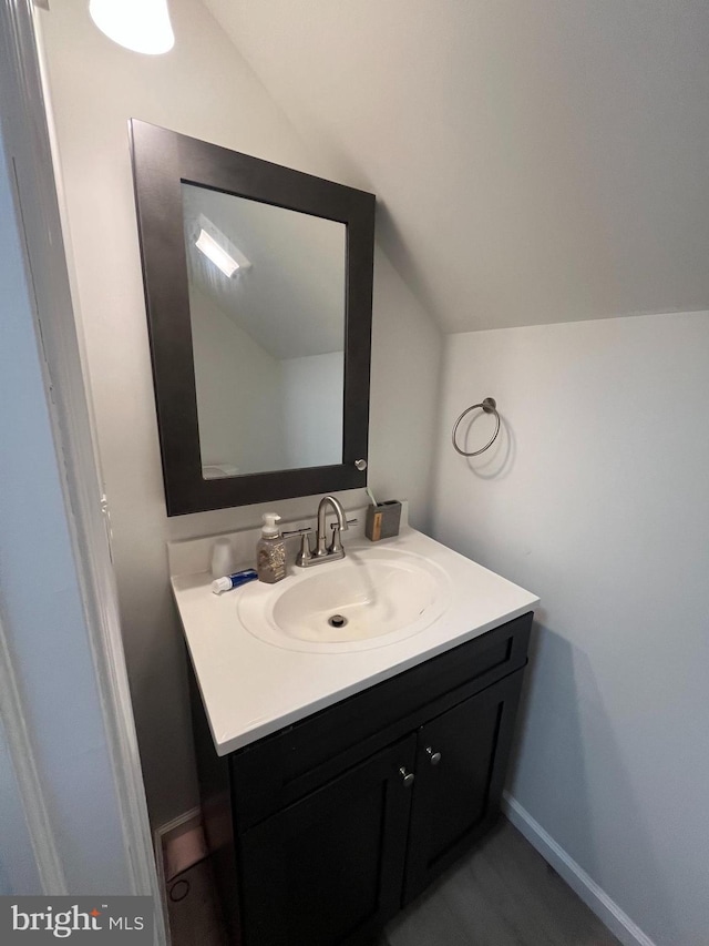 bathroom with vaulted ceiling, vanity, and baseboards