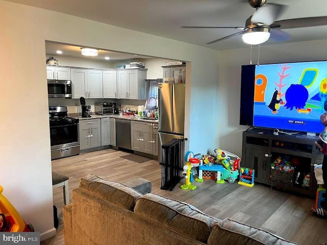 kitchen featuring a toaster, stainless steel appliances, a sink, light countertops, and light wood-type flooring