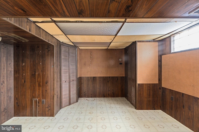 empty room featuring wooden ceiling, a drop ceiling, and wood walls