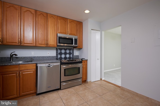 kitchen featuring light tile patterned floors, appliances with stainless steel finishes, sink, and dark stone counters