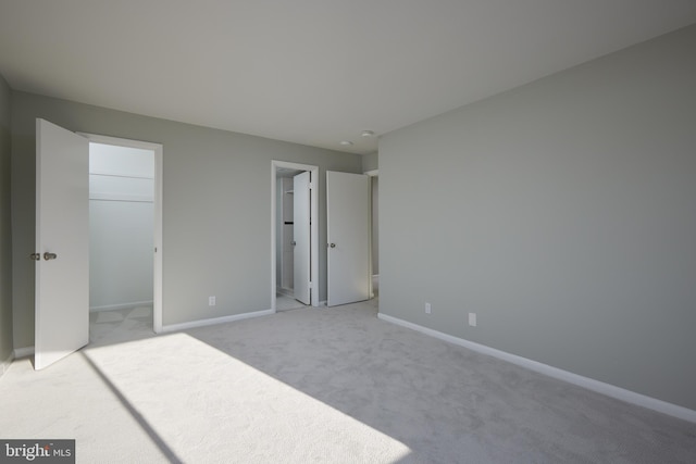 carpeted bedroom with ensuite bath, a walk in closet, and a closet