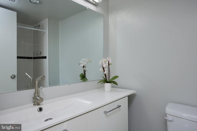 bathroom with vanity, toilet, and a tile shower