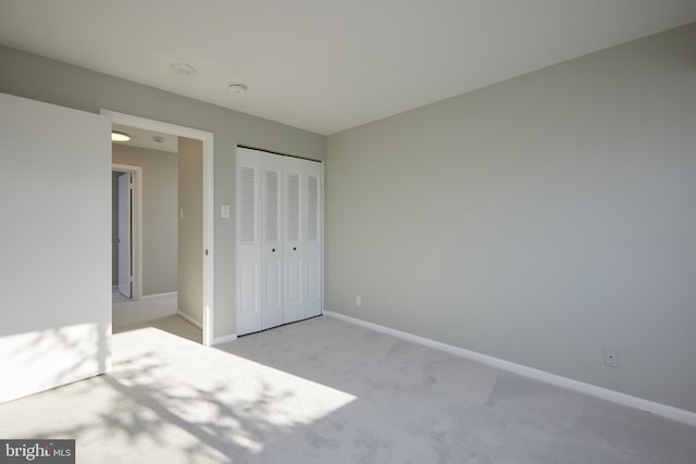 unfurnished bedroom with a closet and light carpet