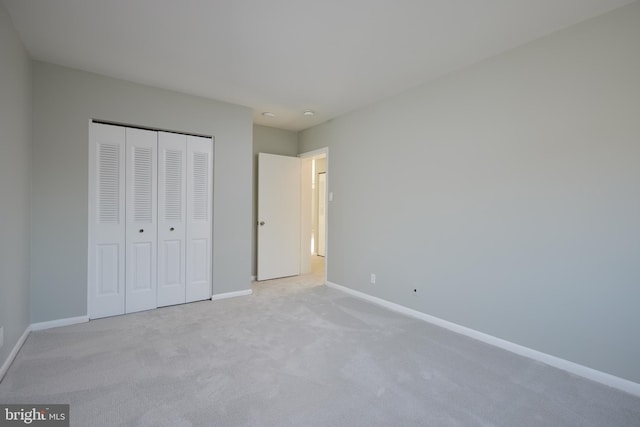 unfurnished bedroom featuring light colored carpet and a closet