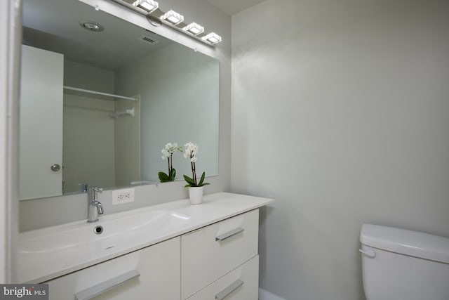 bathroom with walk in shower, vanity, and toilet