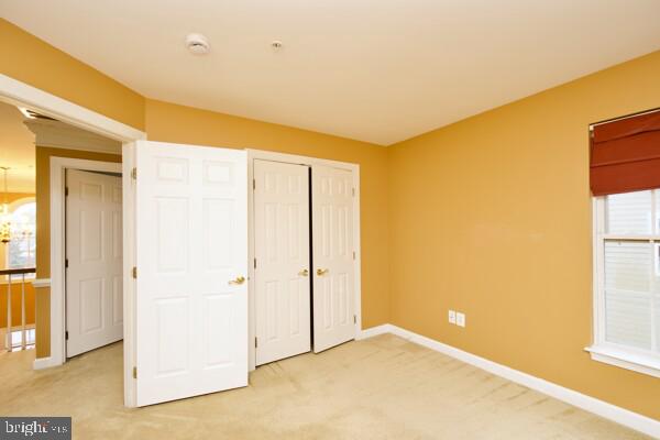 unfurnished bedroom with light colored carpet and a closet