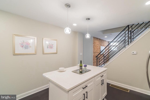 kitchen featuring visible vents, a center island, decorative light fixtures, light countertops, and white cabinetry