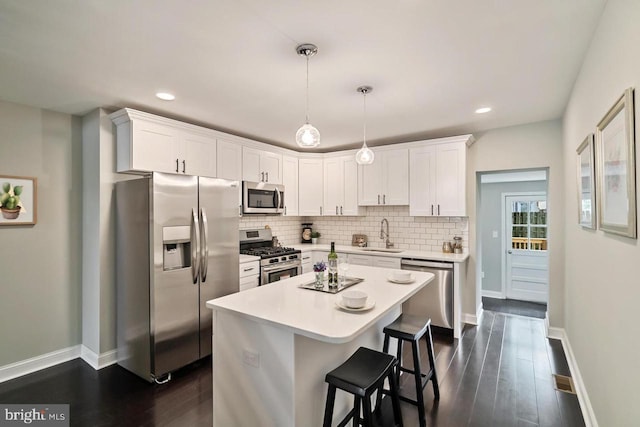 kitchen with stainless steel appliances, light countertops, white cabinetry, and decorative light fixtures