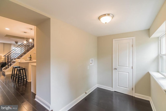 hallway featuring dark wood-style floors, stairway, and baseboards