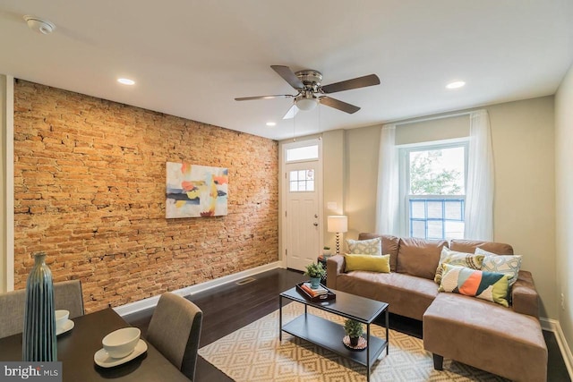 living room featuring a healthy amount of sunlight, brick wall, wood finished floors, and recessed lighting