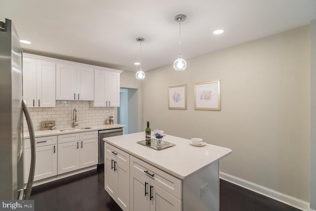 kitchen with stainless steel appliances, a sink, white cabinets, hanging light fixtures, and light countertops