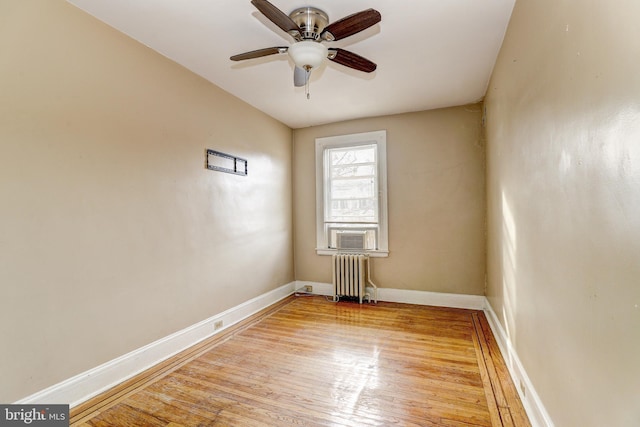 spare room with ceiling fan, radiator heating unit, and light wood-type flooring