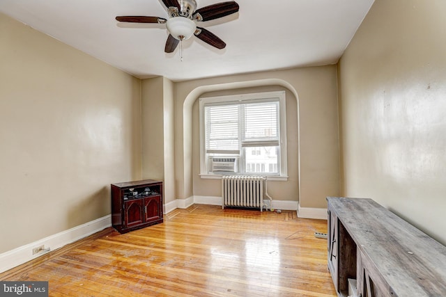 empty room with cooling unit, ceiling fan, radiator heating unit, and light hardwood / wood-style floors