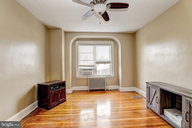 unfurnished room featuring cooling unit, radiator heating unit, ceiling fan, and light hardwood / wood-style flooring