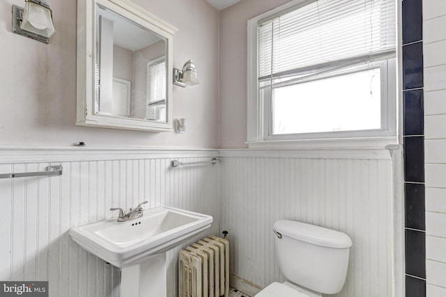 bathroom with plenty of natural light, radiator heating unit, and toilet