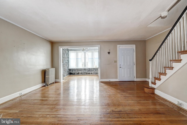 foyer entrance with crown molding, radiator, and hardwood / wood-style flooring