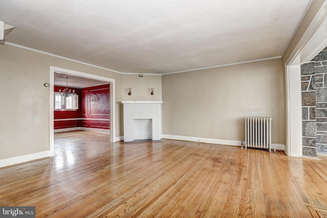 unfurnished living room featuring hardwood / wood-style flooring, crown molding, a brick fireplace, and radiator heating unit