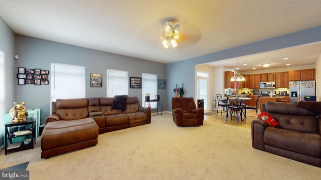 carpeted living room featuring ceiling fan with notable chandelier