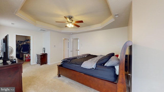 bedroom with ceiling fan, a raised ceiling, a closet, and a walk in closet