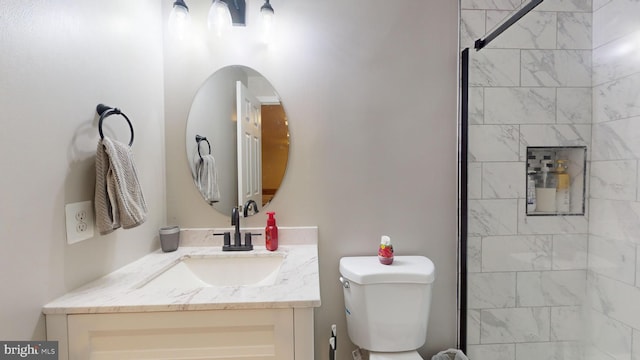 bathroom with vanity, a tile shower, and toilet