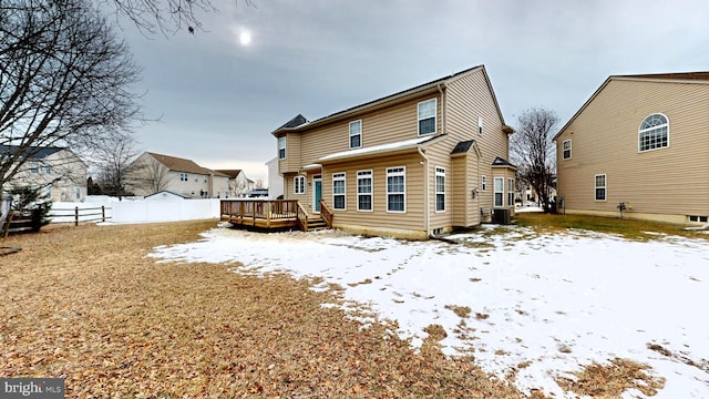 snow covered rear of property with a wooden deck and central AC