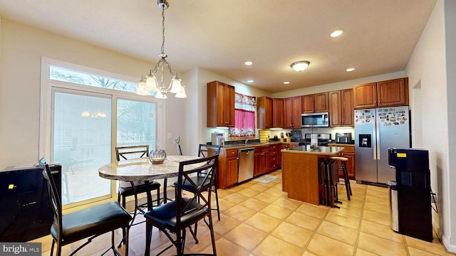 kitchen featuring light tile patterned floors, sink, hanging light fixtures, stainless steel appliances, and a kitchen island