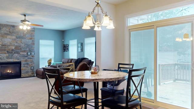 carpeted dining space featuring ceiling fan and a stone fireplace