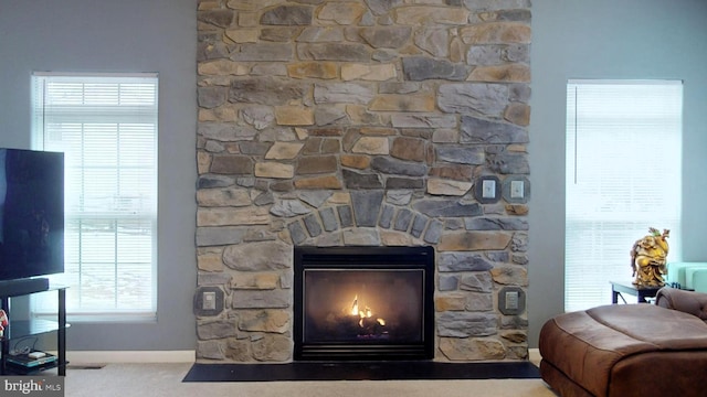 room details featuring a stone fireplace and carpet