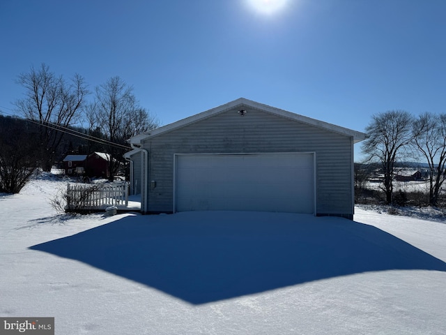 view of snow covered exterior with an outbuilding and a garage