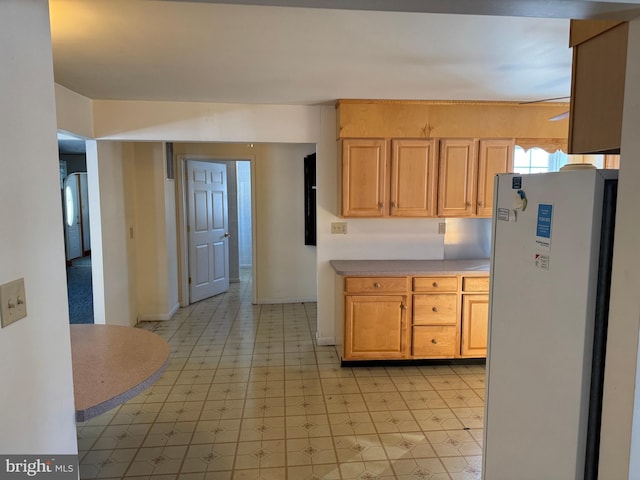 kitchen with white refrigerator, refrigerator, and light brown cabinetry