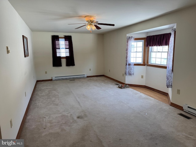 spare room featuring light carpet, a baseboard heating unit, plenty of natural light, and ceiling fan