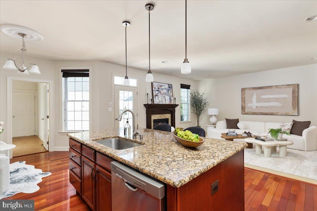 kitchen with stainless steel dishwasher, an island with sink, decorative light fixtures, and sink