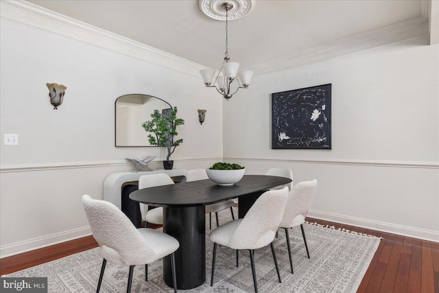 dining space featuring crown molding, wood-type flooring, and an inviting chandelier