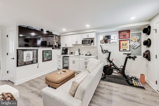 interior space with beverage cooler, sink, and light hardwood / wood-style flooring