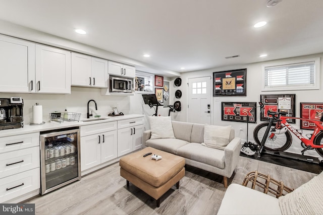 living room with sink, wine cooler, and light wood-type flooring