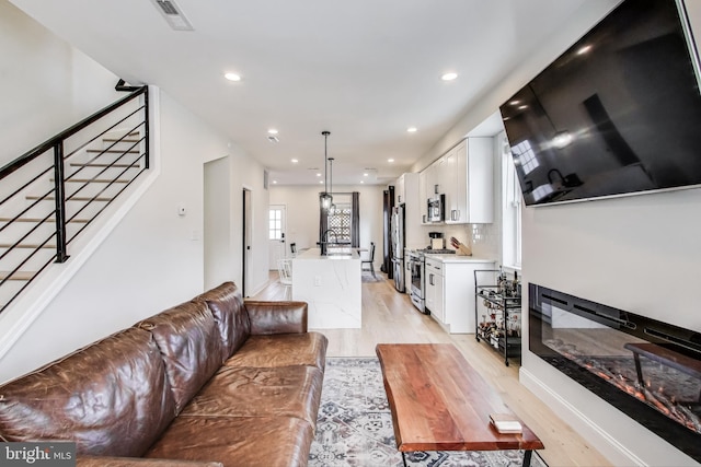 living room featuring sink and light hardwood / wood-style flooring