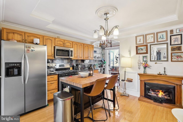 kitchen with wooden counters, stainless steel appliances, tasteful backsplash, light hardwood / wood-style floors, and decorative light fixtures